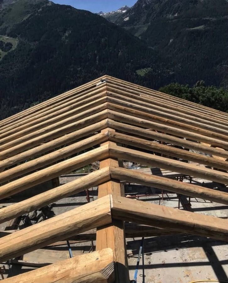 Charpente de toiture en bois massif vue depuis l’arête, chantier en montagne